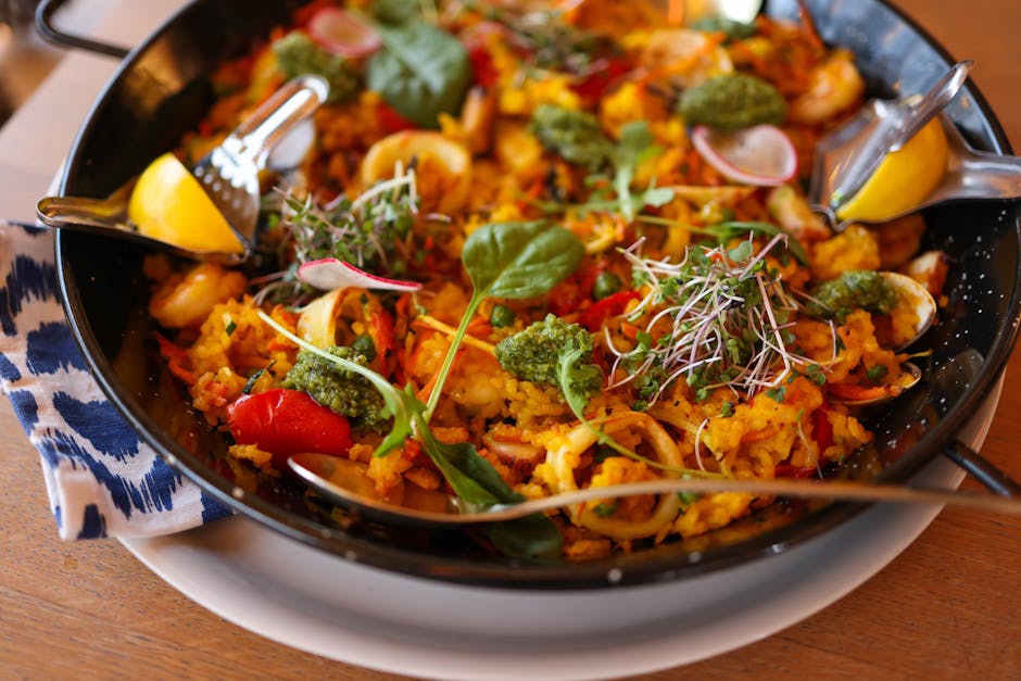 Delicious vibrant paella with seafood, vegetables, and herbs in a pan, ready to serve.